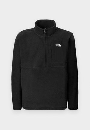 Zwarte fleece pullover met een hoge kraag, ritssluiting aan de voorkant tot de helft en een borstzak aan de linkerkant. Bevat een gestructureerde stof en een logo op de zak.