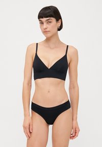 Black bralette with thin straps and a V-neck design, paired with black bikini briefs featuring a soft waistband. Smooth texture overall.