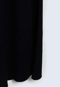 Tessuto a maglia nera con texture a costine, che si drappeggia morbidamente. Il bordo presenta una leggera curvatura, creando una silhouette slanciata.