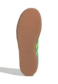 Zelená podrážka tenisky s textúrovaným gumovým povrchom a mierne zakriveným okrajom. Horná časť je zelená s jasne žltými akcentmi.