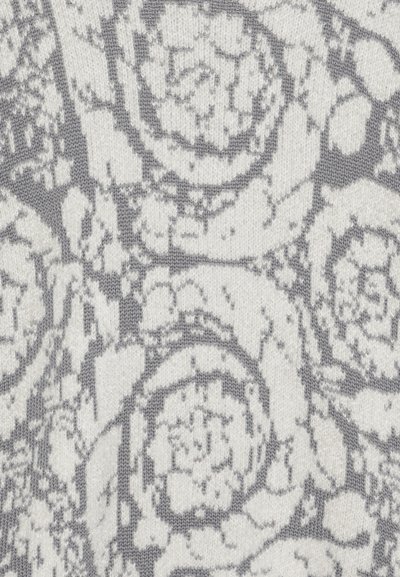 Tissu tricoté avec un motif floral dans des teintes de gris et écru, présentant une surface texturée et des motifs circulaires ressemblant à des roses.