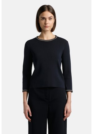 Pull en tricot bleu marine avec des manches trois-quarts, présentant un corps texturé et un point de chaîne décoratif au niveau du col et des poignets.