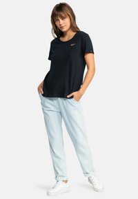 Sort kortærmet t-shirt med rund halsudskæring og Roxy-logo. Sammen med lys blå løstsiddende bukser og hvide platform-sneakers.