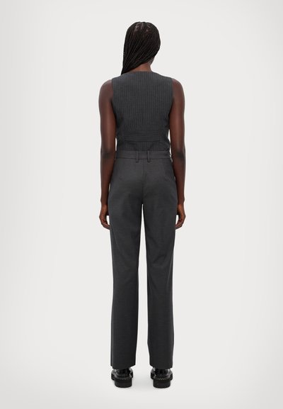 Grijze geribbelde mouwloze top met een nauwsluitend ontwerp, gecombineerd met hoge grijze broeken. De outfit heeft een gladde textuur en minimale accenten.