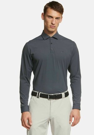 Donkergrijze polo met lange mouwen en drie knopen, gemaakt van soepel materiaal. Gekleed met lichte broeken en een zwarte geweven riem.