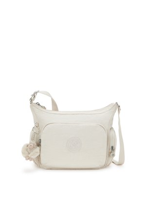 Beige crossbody bag made of soft fabric with a zip closure, featuring an emblem, a front pocket, and a furry keychain attached.