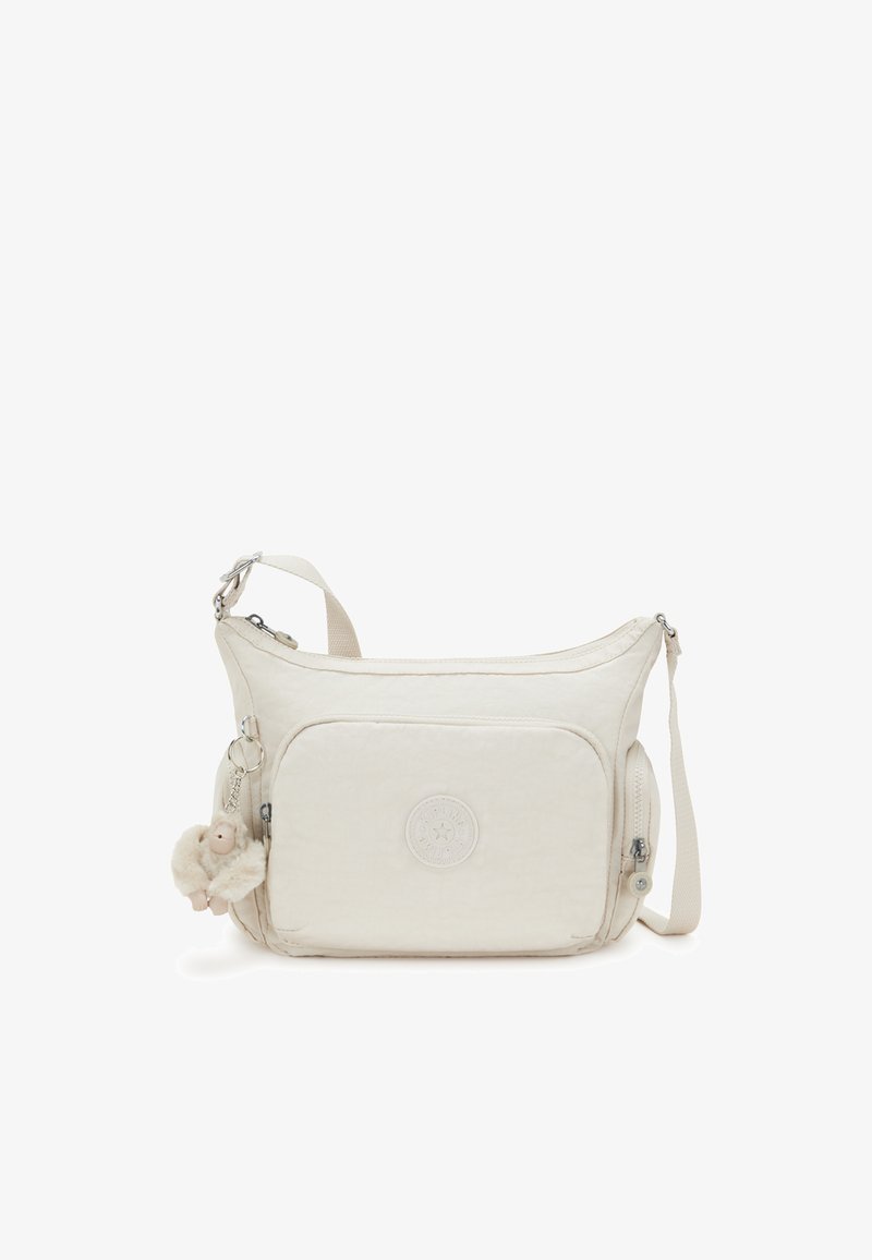 Borsa a tracolla beige realizzata in morbido tessuto con chiusura a zip, dotata di un emblema, una tasca frontale e un portachiavi peloso attaccato.