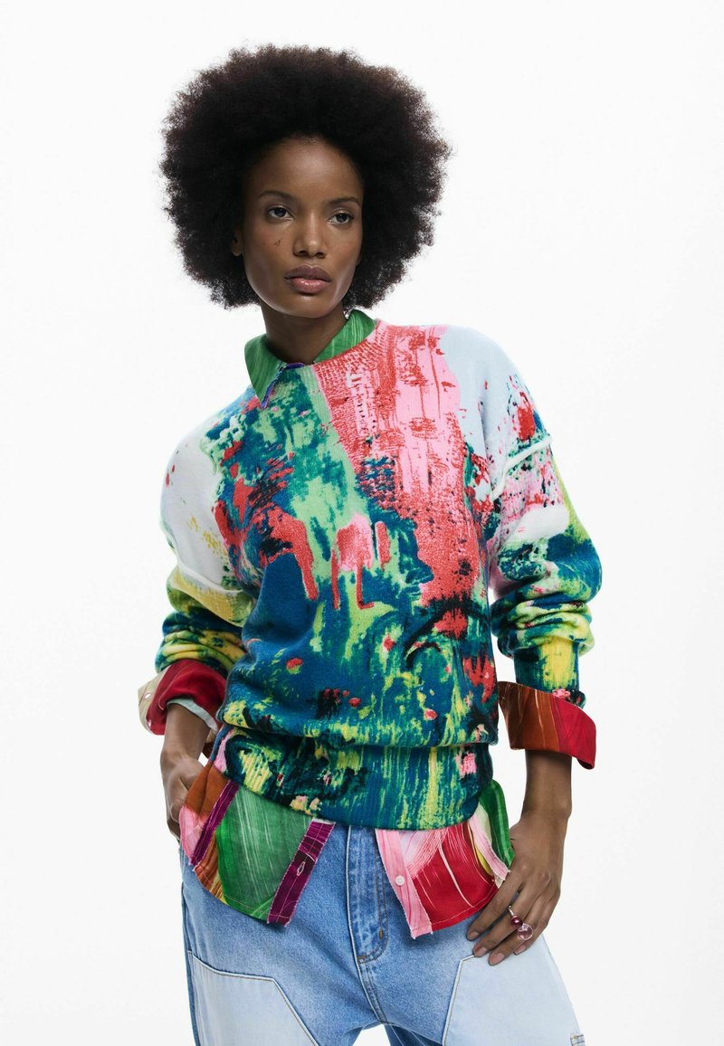 Suéter de punto colorido con patrones abstractos en azul, verde, rosa y rojo. Presenta un cuello verde y colores de acento audaces en las mangas.