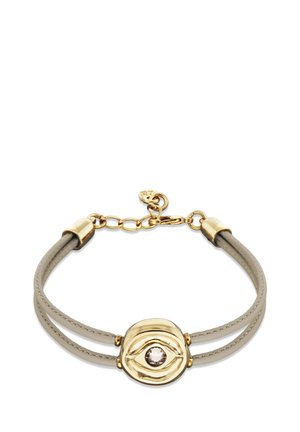 Bracelet doré et beige avec une double lanière et un pendentif central rond en or, orné d'un motif en forme d'œil et d'une pierre précieuse claire.