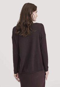 Maglietta a maniche lunghe color bordeaux, realizzata in un tessuto morbido e liscio. Presenta una vestibilità comoda e un orlo arrotondato, con spalle scese e fessure laterali.
