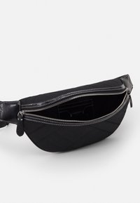 Marsupio in tessuto nero con zipper argentata parzialmente aperta, che mostra l'interno nero e una piccola tasca interna, su sfondo bianco.