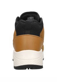 Baskets en daim marron avec des accents en maille noire, semelle en caoutchouc et semelle intermédiaire blanche. Dispose d'une languette au niveau du talon pour un enfilage facile.