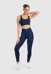 Marine sporttop en bijpassende hoge tailleleggings van rekbaar materiaal. De top heeft een ronde halslijn en brede schouderbanden.