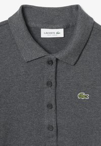 Polo shirt côtelé gris foncé avec une patte de boutonnage à trois boutons, boutons noirs et un logo de crocodile brodé vert sur la poitrine gauche.