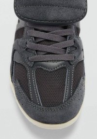 Crna atletska cipela s mrežastim gornjim dijelom, aksesorima od antilopa, okruglim vezicama i podstavljenim jezikom; ima teksturiranu potplate i kontrastne šavove.