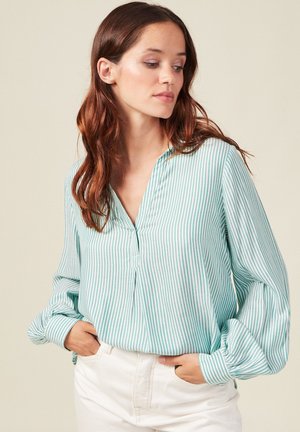 Blusa a rayas en tonos verde azulado con mangas largas, frente abotonado y corte relajado. Fabricada en una tela suave con un ligero brillo.