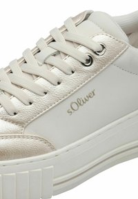 Adidași albi cu accente din piele metalizată, parte superioară texturată cu șireturi, logo argintiu, talpă groasă albă și vârf rotund.