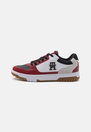 Sneakers featuring a mix of materials: red suede and black leather upper, white leather accents, textured gray panel, and a gum rubber sole.
