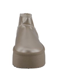 Beige schoenen met satijnen afwerking, een afgeronde voorkant, elastische zijkantopening en een dikke, gestructureerde platformzool. Geen zichtbare veters of hardwaredetails.