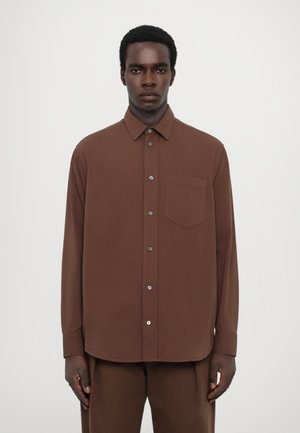 Brown, long-sleeve button-up shirt with a collar, single chest pocket, smooth texture, and rounded hem, paired with matching trousers.