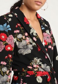 Blazer s květinovým potiskem na černém pozadí, s živými červenými, růžovými a modrými květinami, fitted střih a detail vázání v pase.