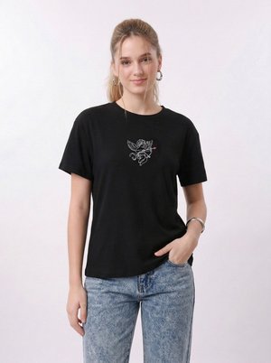 Νεαρή γυναίκα που φοράει μαύρο μπλουζάκι με λευκό χερουβίμ που κρατά ροζ βέλος, ανοιχτό μπλε τζιν, κρίκους στα αυτιά και ασημένιο βραχιόλι.