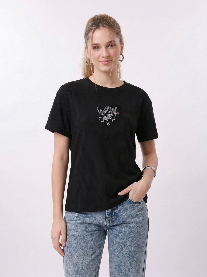 Νεαρή γυναίκα που φοράει μαύρο μπλουζάκι με λευκό χερουβίμ που κρατά ροζ βέλος, ανοιχτό μπλε τζιν, κρίκους στα αυτιά και ασημένιο βραχιόλι.