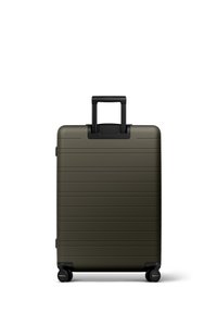 Valise rigide en vert olive, avec des rainures horizontales, une poignée télescopique et quatre roues noires pour la mobilité.