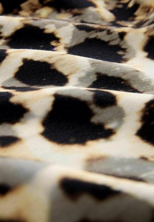Leopard print fabric featuring a blend of black spots and light beige background with a soft textured surface, arranged in wavy folds.