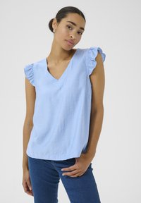 Haut sans manches bleu clair avec décolleté en V et manches capes à volants. Fabriqué en tissu texturé, il présente une coupe décontractée et un design informel.