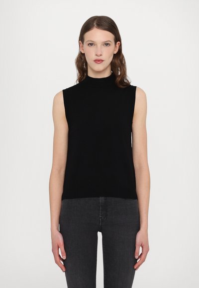 Haut sans manches noir avec un col haut, fabriqué en tissu lisse. Silhouette ajustée avec une texture unie, associé à un jean sombre.