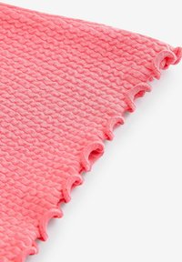 Korallrosa textil med struktur och vågigt mönster, med ett flikigt kant. Mjukt material med en lätt upphöjd design över hela ytan.