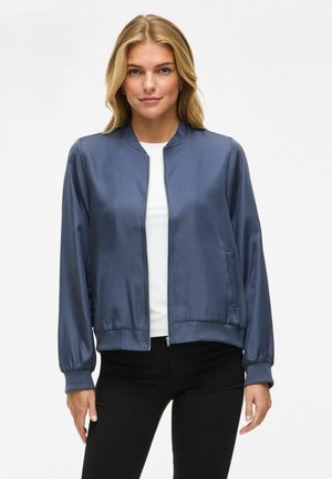 Giacca bomber in satin blu navale con zip frontale, polsini a coste e tasche laterali. La texture liscia e il design aderente ne esaltano la struttura.