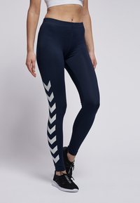 Marinblå leggings med en slät textur har en kontrasterande vit chevrondesign längs utsidan, utformade för aktiv träning.