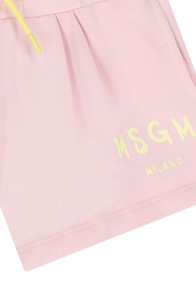 Pantalones cortos de tela rosa con cordón amarillo y texto impreso en amarillo "MSGM MILANO" cerca del dobladillo en la pierna derecha.