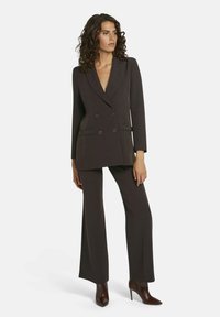 Donker op maat gemaakt pak met een dubbelzijdige blazer, notch revers en wijde broekspijpen. Soepele stof en minimalistisch ontwerp; geen patronen.