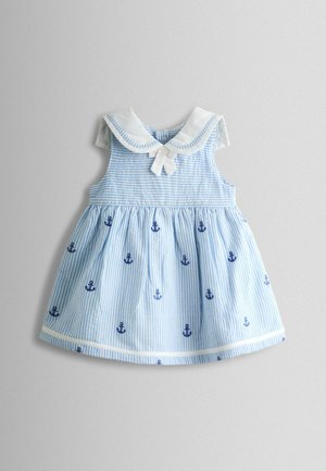Rochie cu dungi albastre deschis, cu un guler alb, decorată cu un model de ancora. Are o fustă adunată și un detaliu cu fundă în față.