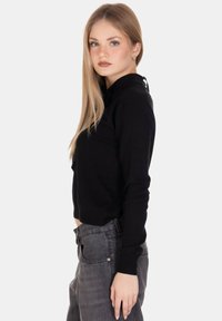 Maglione lavorato a maglia nero con colletto, vestibilità slim, maniche lunghe e finitura testurizzata, abbinato a pantaloni in denim grigi.