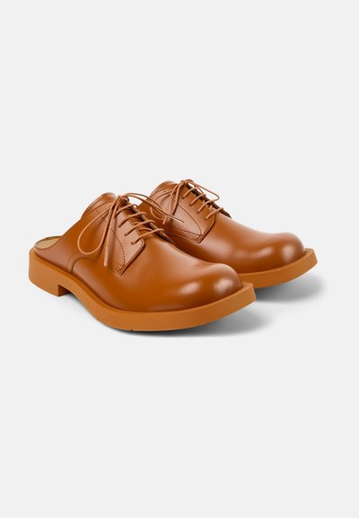 Bruna läderballerinaskor med en slät finish, rund tå och kontrasterande gummisula. Har snörningsdetaljer och en minimalisk design.