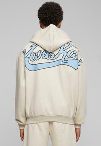 Bežová mikina s kapucňou, na zadnej strane s light blue kurzívou logom. Navrhnuté s kapucňou s šnúrkou a rebrovanými manžetami na rukávoch.