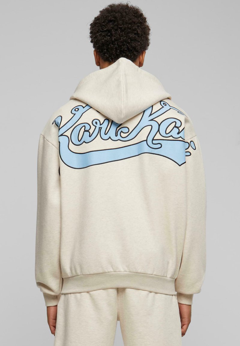 Bežová mikina s kapucňou, na zadnej strane s light blue kurzívou logom. Navrhnuté s kapucňou s šnúrkou a rebrovanými manžetami na rukávoch.