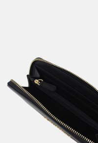Black leather wallet with gold zipper, multiple card slots, and a zippered compartment. Interior has a smooth texture.