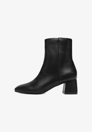 Stivaletto alla caviglia in pelle nera con punta appuntita, tacco a blocco e texture liscia. Design semplice con linee pulite e nessun elemento metallico visibile.