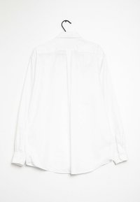 Biała koszula z długim rękawem na wieszaku, z klasycznym kołnierzykiem, mankietami zapinanymi na guziki oraz prostym tyłem z detalem szwowym. Gładki materiał.