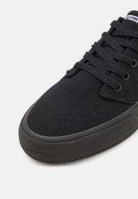 Mustad mustave canvas tossud, millel on tekstureeritud kummitald, ümar nokk ja sobivad paelad, logotägi keele peal ning metallist augud.