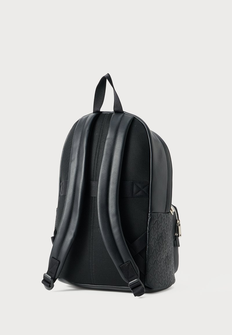 Black backpack featuring a textured side, smooth leather accents, padded straps, and a mesh back for breathability. Zippered side pocket included.