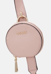 Ronde roze faux leren muntentas met een gouden rits en hardware, voorzien van het geperste merklogo en een zwarte randdetail.