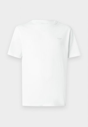 T-shirt en coton blanc avec col rond, manches courtes et un logo gris subtil sur la poitrine gauche. Texture lisse et légère.