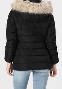 Zwarte donzen jas met een afneembare kap van licht kunstbont, doorgestikt ontwerp en elastische manchetten. Heeft een rechte snit ter hoogte van de taille.