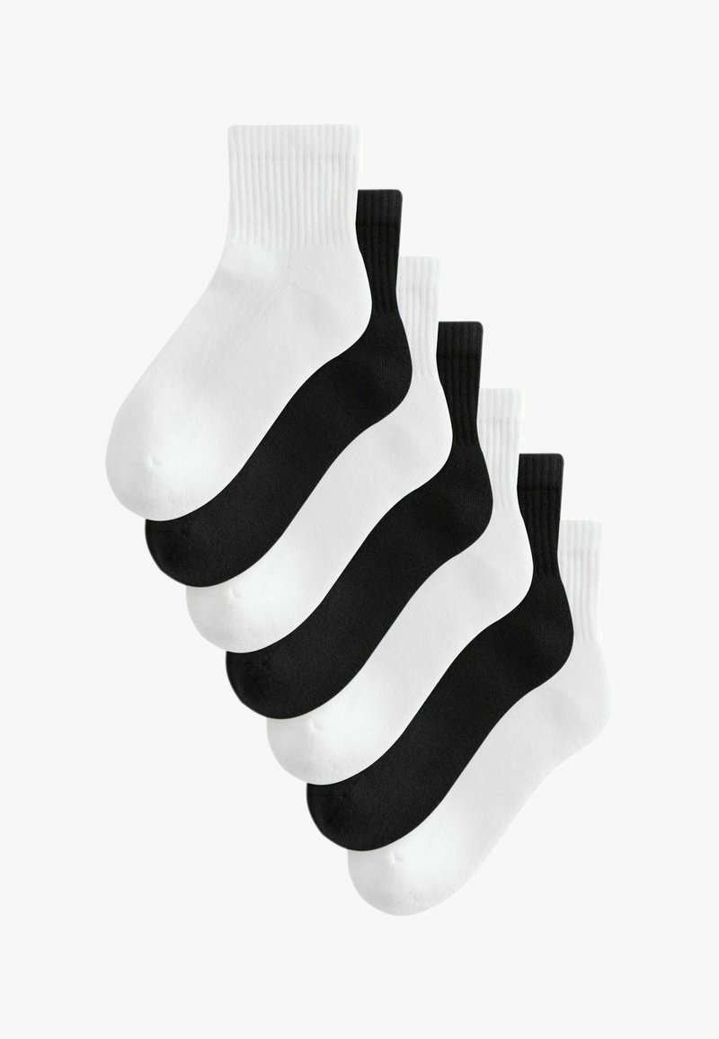 Six paires de chaussettes courtes disposées en alternance en noir et blanc avec des bords côtelés.